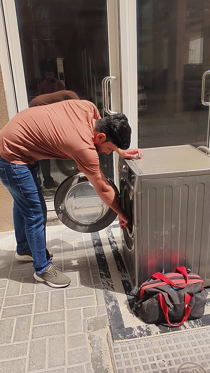 Smart AC Repair technician servicing a front-load washing machine in Dubai